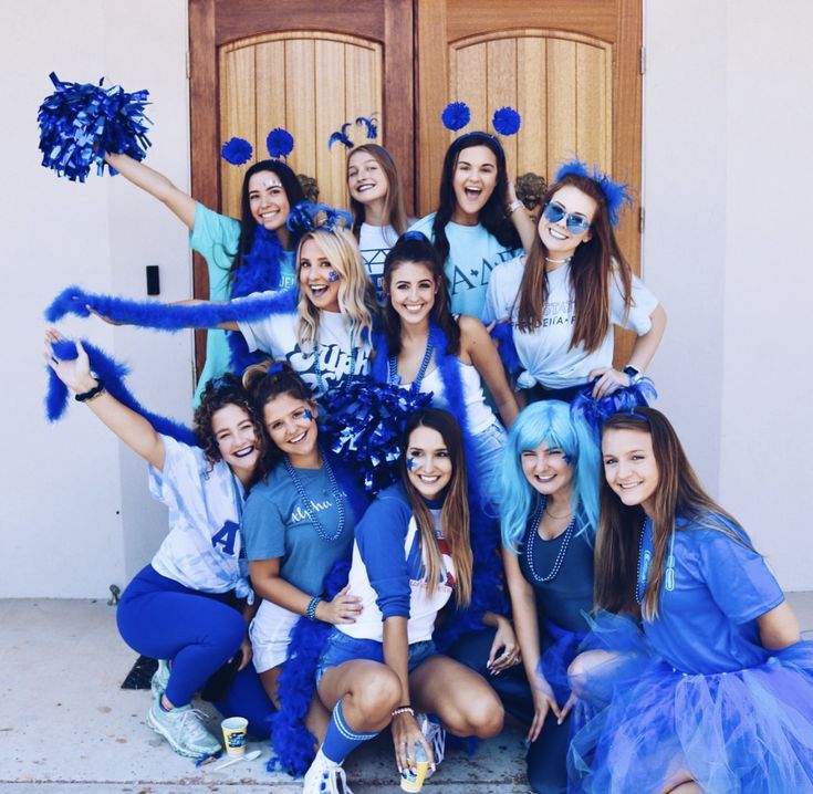 a group of cheerleaders pose for a photo in front of a door with their pom poms