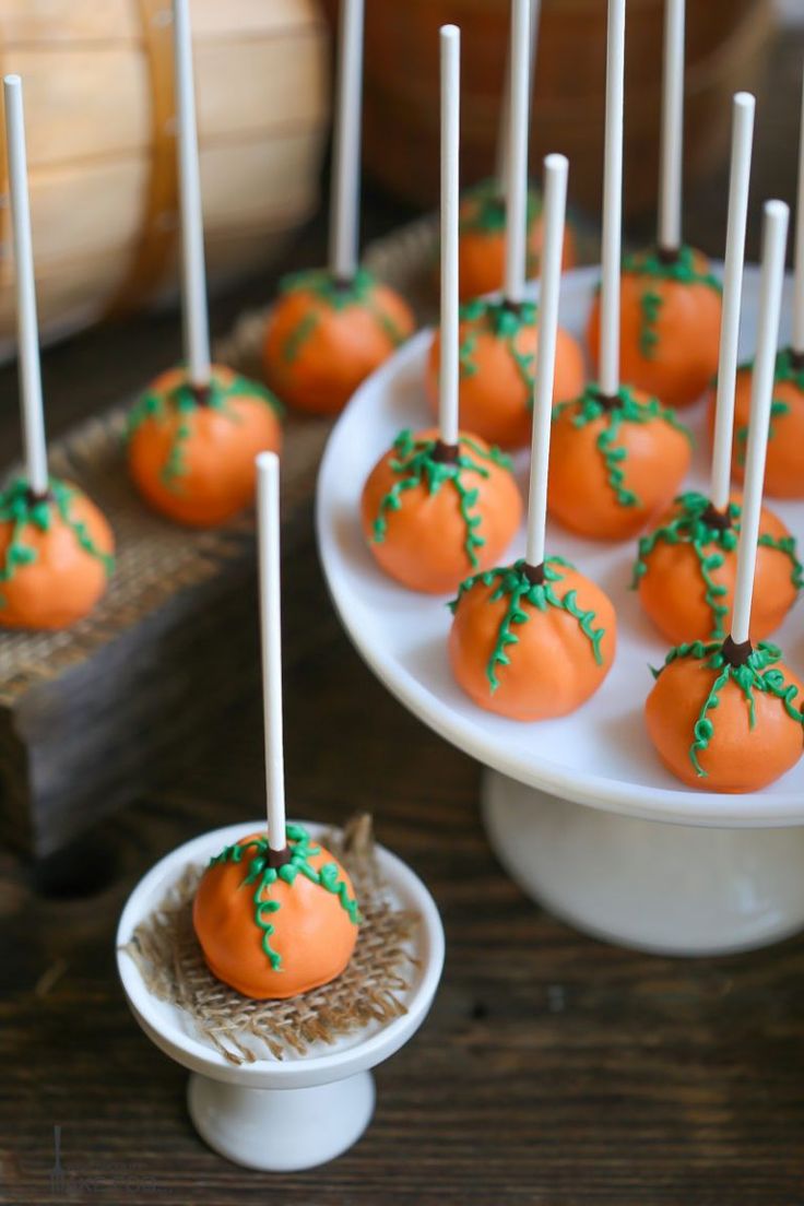 several orange cake pops with green sprinkles on them sitting on a plate