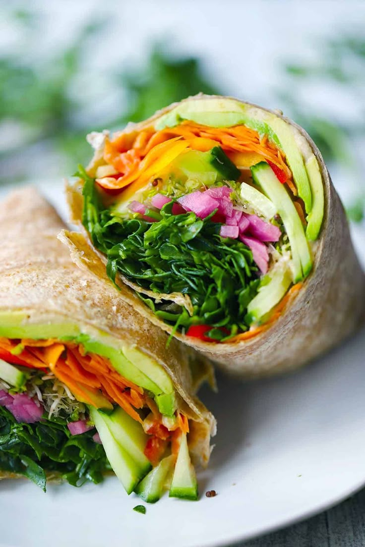 a wrap filled with veggies on top of a white plate