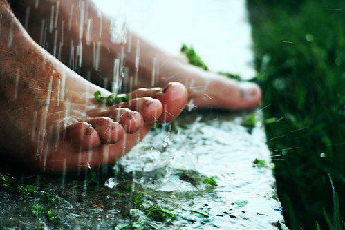 a person standing in the rain with their feet covered by grass and water dripping from them