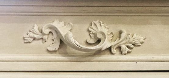 an ornate design on the side of a white cabinet with wood trimmings and carvings