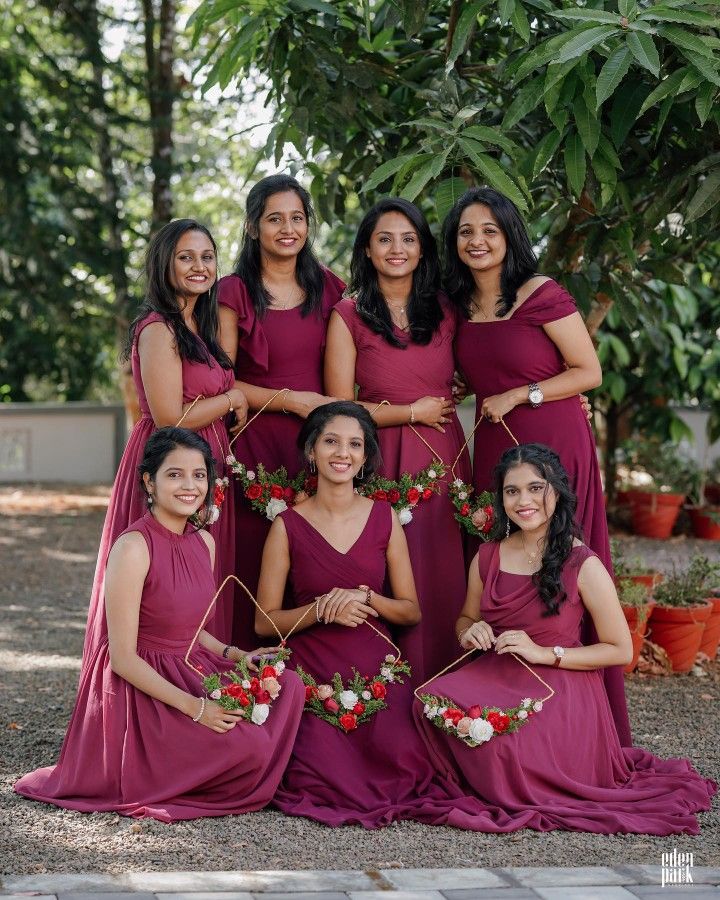 a group of women standing next to each other in maroon dresses with flowers on them