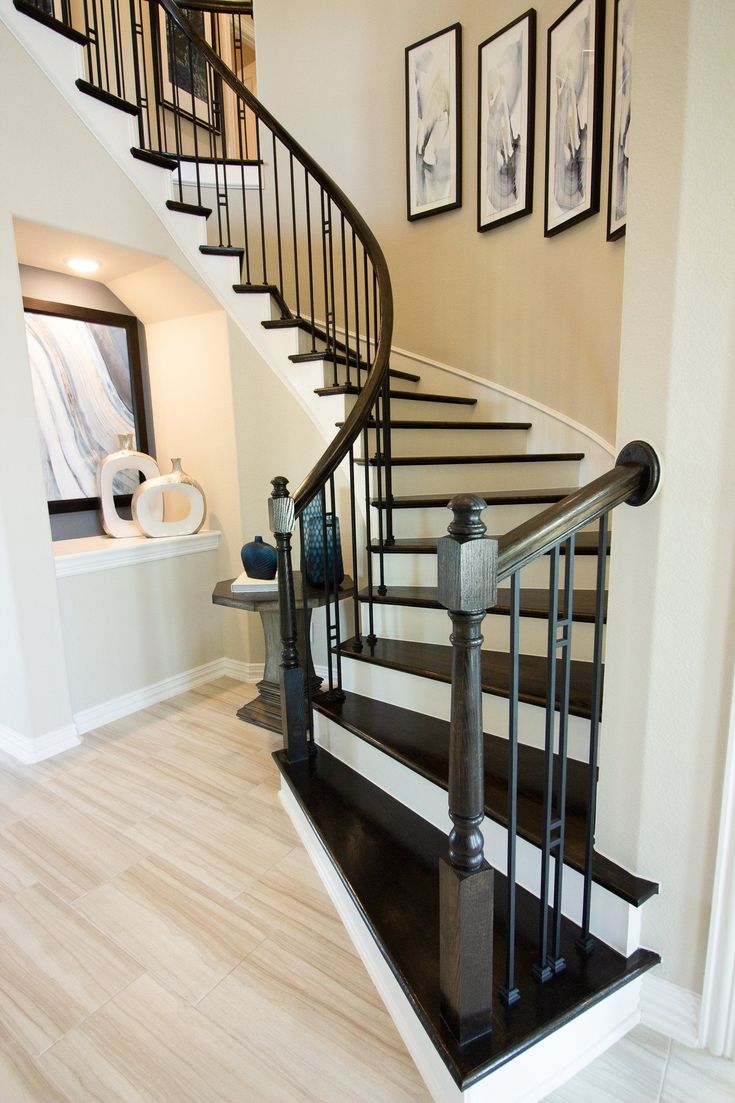 a black and white staircase with pictures on the wall next to it's railing