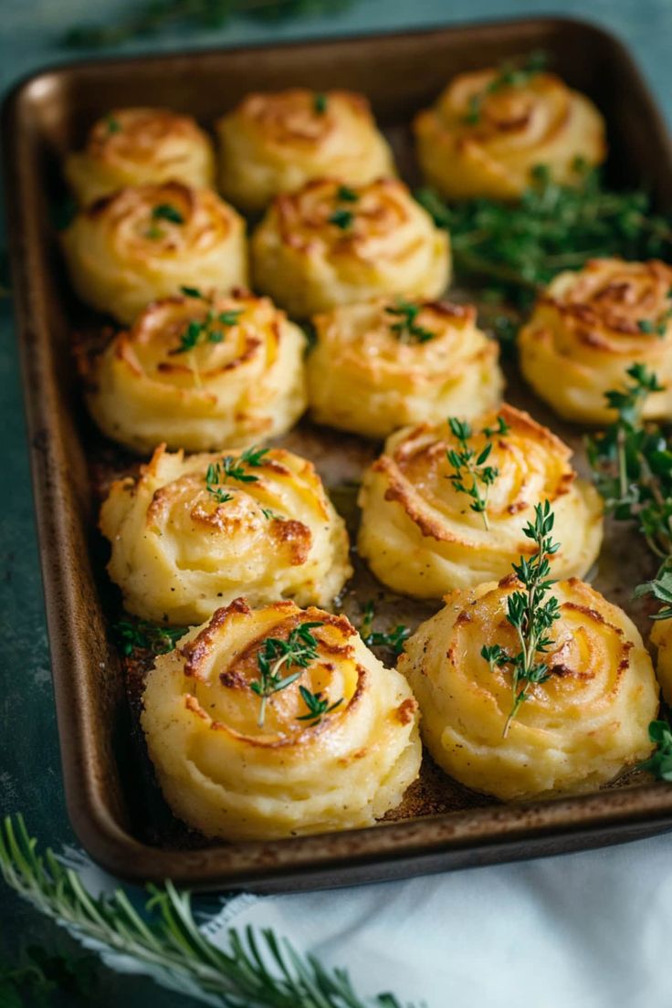 some food that is sitting on a baking pan with green sprigs around it