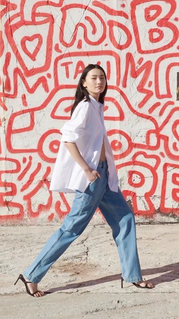 a woman walking in front of a graffiti wall