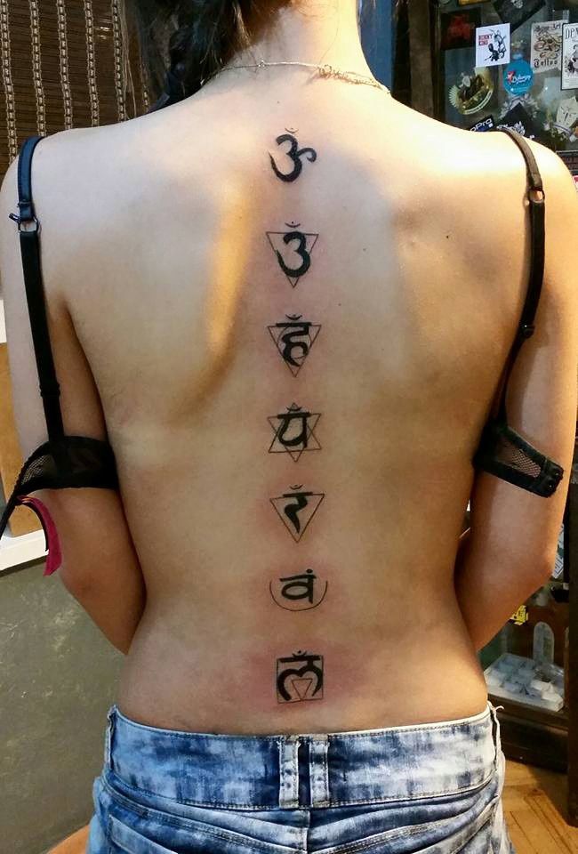 the back of a woman's body with seven chakras tattooed on it