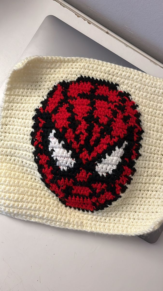 a crocheted dishcloth with a red and white ball on it