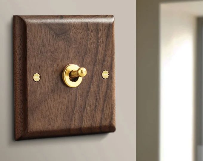 a wooden light switch with two brass knobs on the wall next to a window