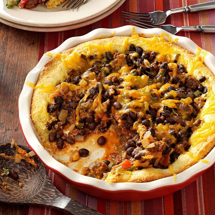 a casserole dish with black beans, cheese and meat in it on a table