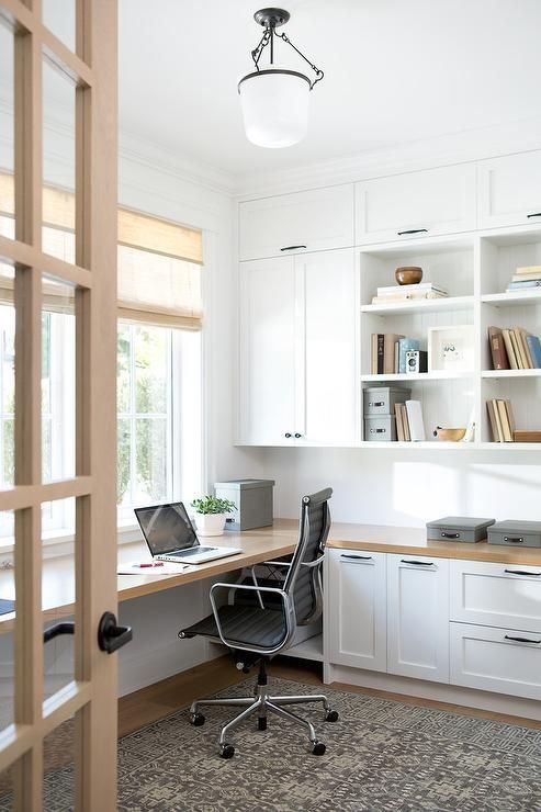 an image of a home office with white cabinets and drawers on the left side of the room