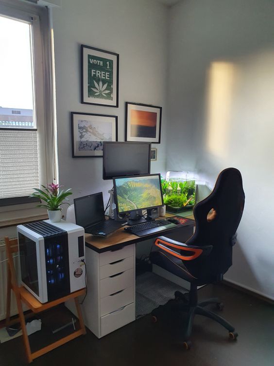 a home office with two computers and a fish tank