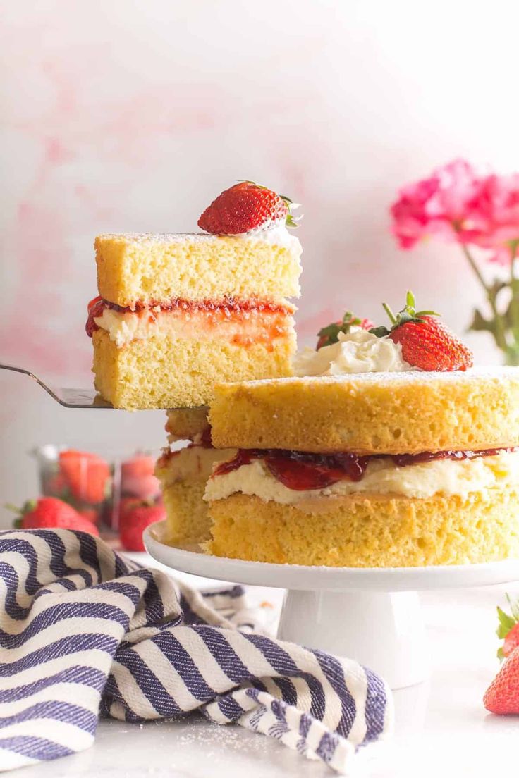 a slice of strawberry layer cake on a white plate with strawberries next to it