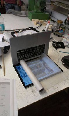 an open laptop computer sitting on top of a desk next to papers and other items