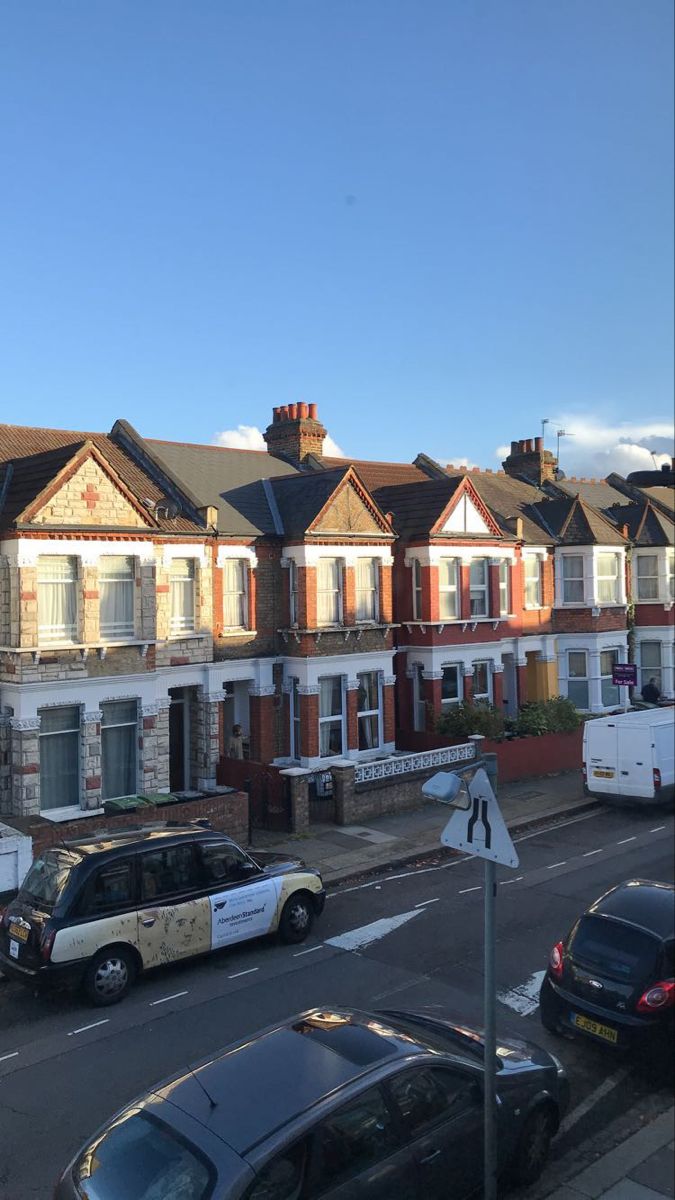 cars are parked on the side of the road in front of row houses with windows