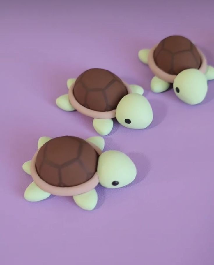 three plastic turtle figurines sitting on top of a purple surface