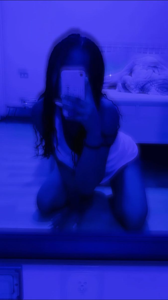 a woman taking a selfie with her cell phone in front of a blue light