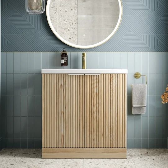 a bathroom with blue and white walls, a round mirror over the sink and a wooden cabinet