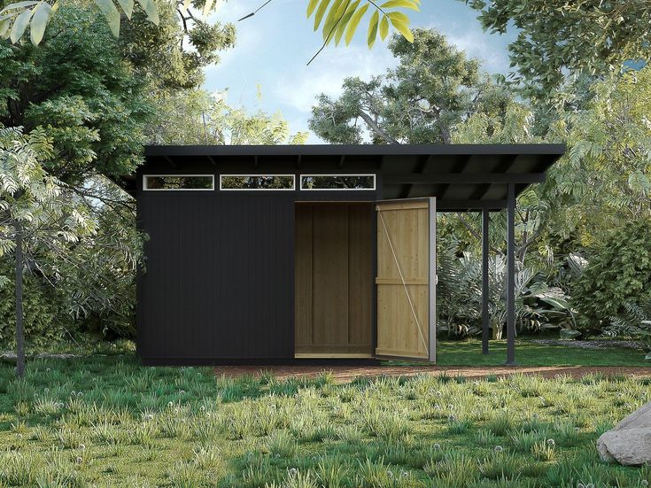 a small black shed sitting on top of a lush green field