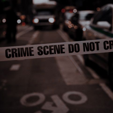 a police tape is taped off on the side of a street with parked cars in the background