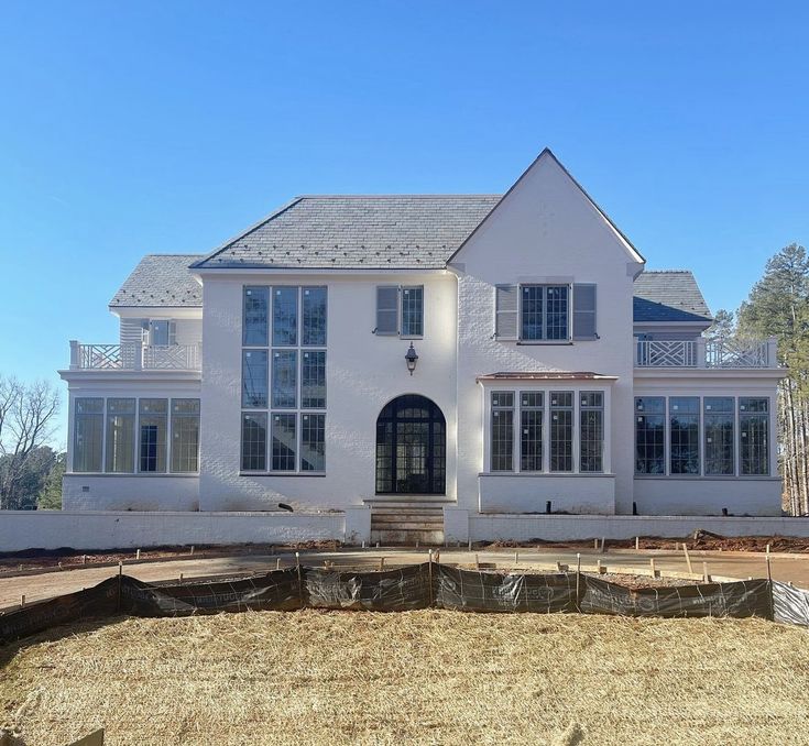 a large white house sitting on top of a dry grass field