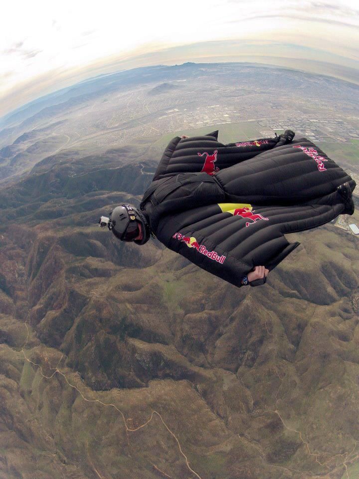 the parachute is in the shape of a red bull kite flying high up in the sky