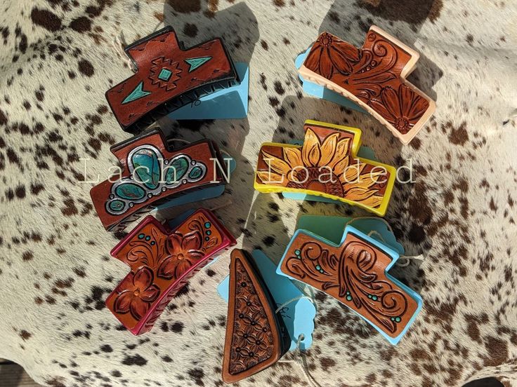 several different colored and decorated wooden pieces on a cowhide surface