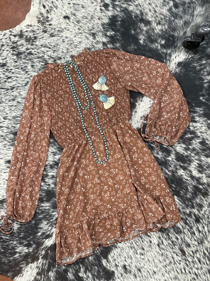 This beautiful long sleeve floral print smocked bodice mini dress is one we know you will love in stunning brown tones! This dress is perfect for any occasion with great details of ties and sheer sleeves! Chic Brown Long Sleeve Dress For Spring, Chic Brown Long Sleeve Spring Dress, Brown Long Sleeve Bohemian Mini Dress, Fall Mini Dress With Smocked Cuffs And Long Sleeves, Brown Flowy Long Sleeve Dress, Elegant Brown Dress With Smocked Back, Brown Floral Print Mini Dress For Fall, Bohemian Long Sleeve Mini Dress With Smocked Bodice, Bohemian Mini Dress With Smocked Bodice And Long Sleeves