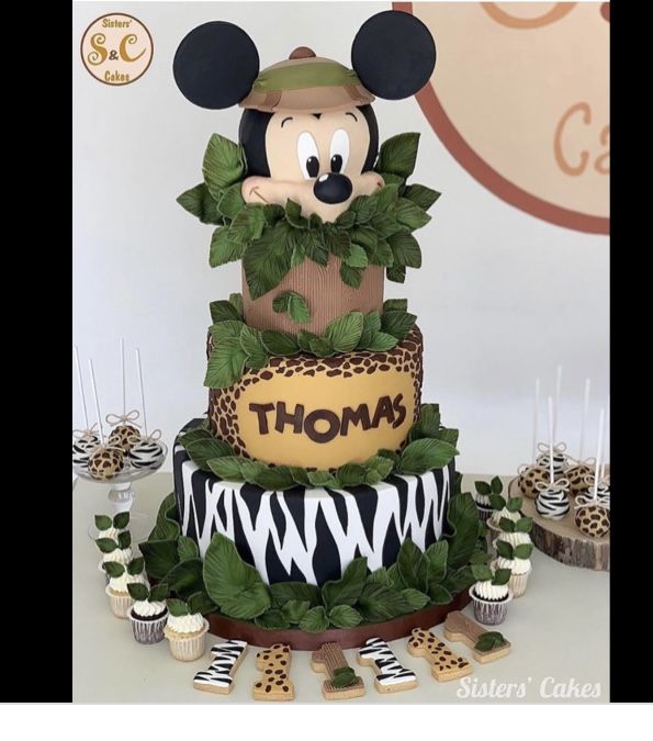 a mickey mouse birthday cake with cupcakes and decorations