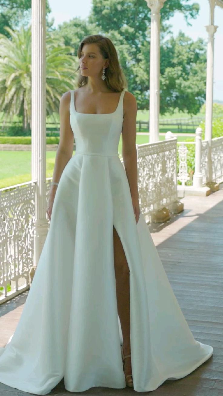 a woman in a white dress standing on a porch