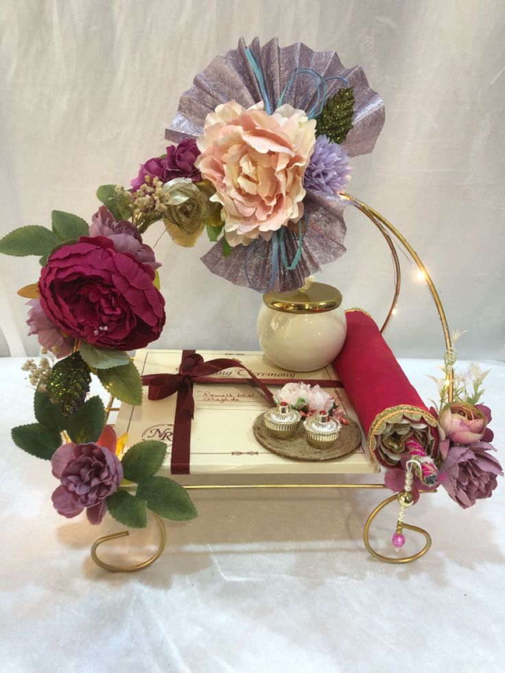 an arrangement of flowers in a vase on a table with other items and decorations around it