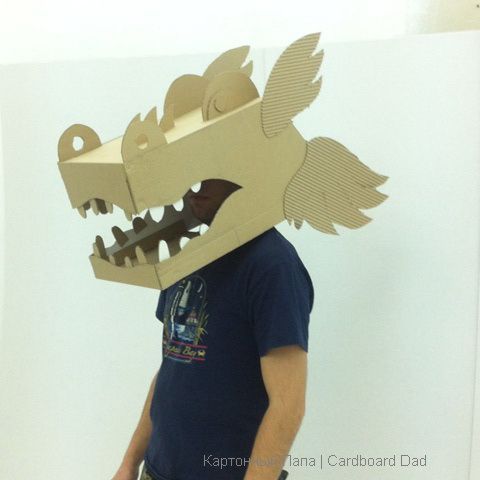 a man is wearing a cardboard dinosaur mask