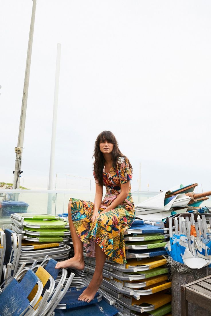 a woman sitting on top of a pile of surfboards