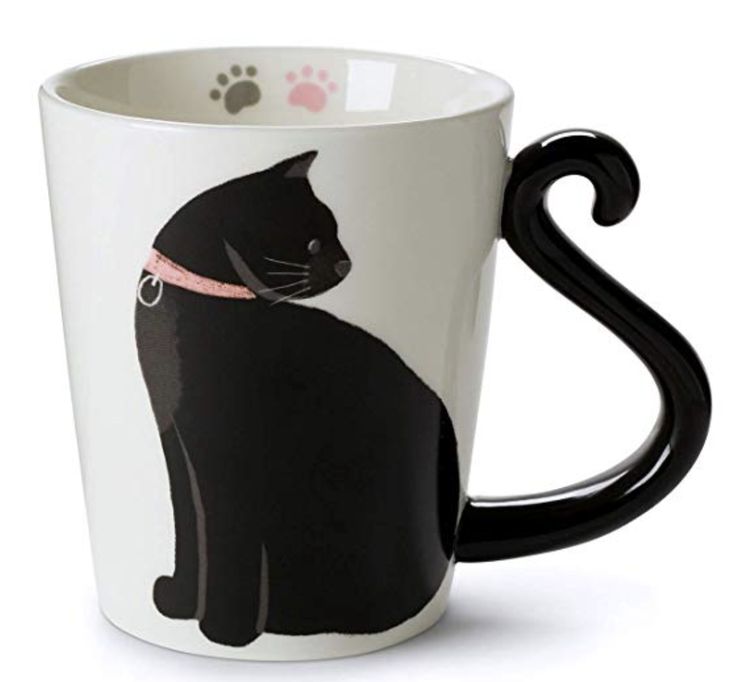 a black cat with a pink collar on its neck is sitting in a coffee cup