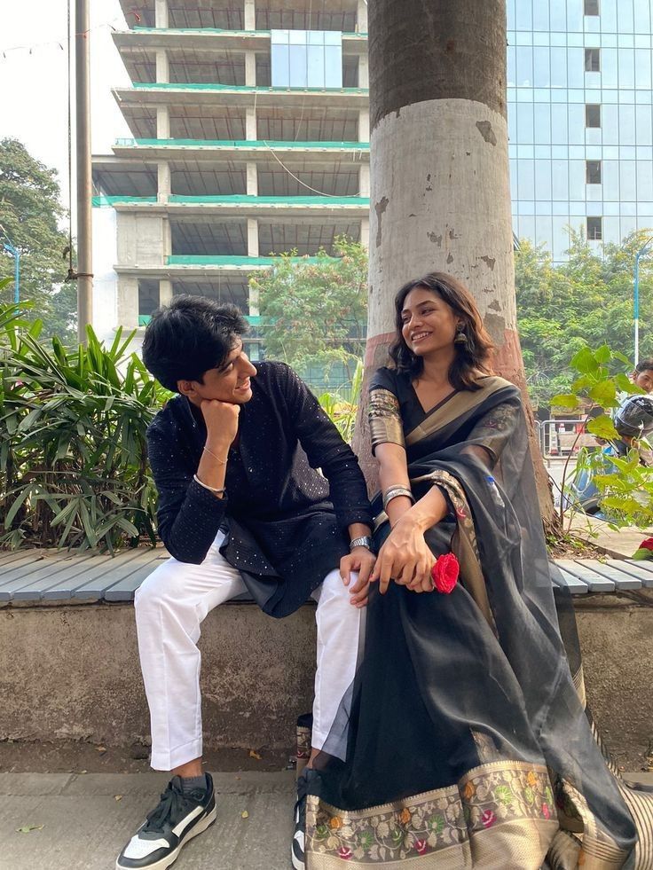 two people sitting next to each other on a bench in front of a tall building