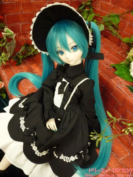 a doll sitting on top of a wooden floor wearing a black and white dress with long blue hair