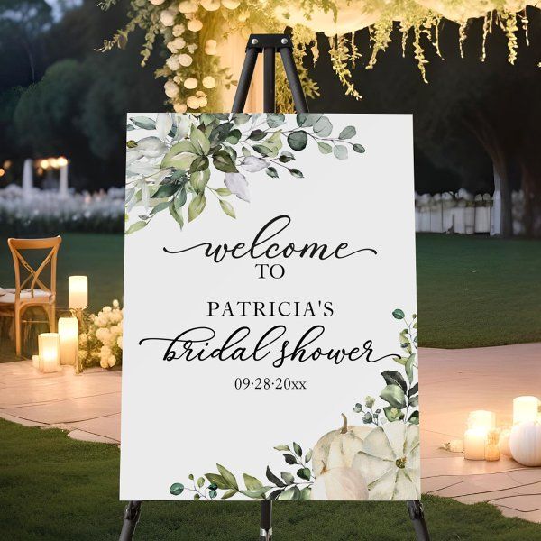 a welcome sign for a bridal shower with candles and flowers on the ground behind it