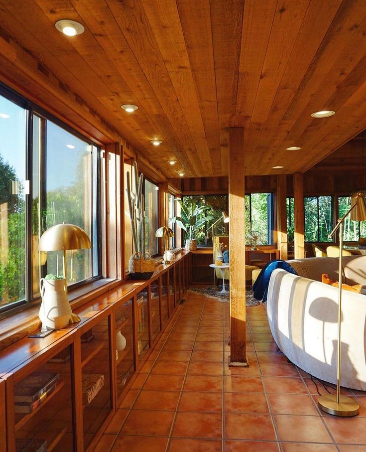 a living room filled with lots of furniture next to a large window on top of a wooden ceiling