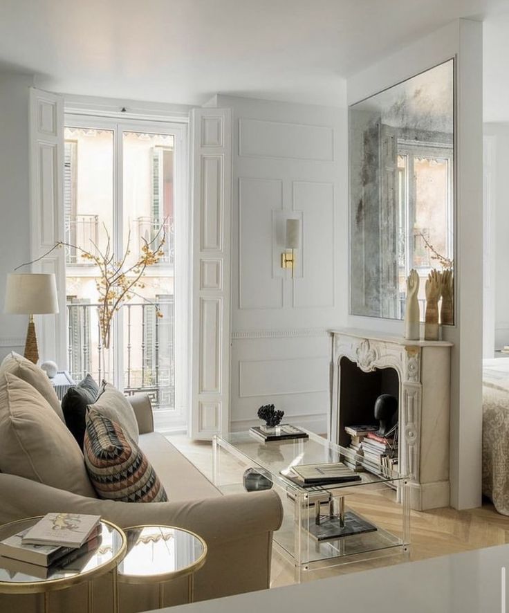 a living room filled with furniture and a fire place in front of a mirror on the wall