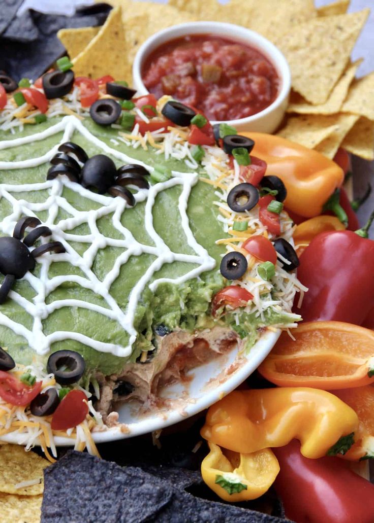 an enchilada dish with black olives, tomatoes, peppers and tortilla chips