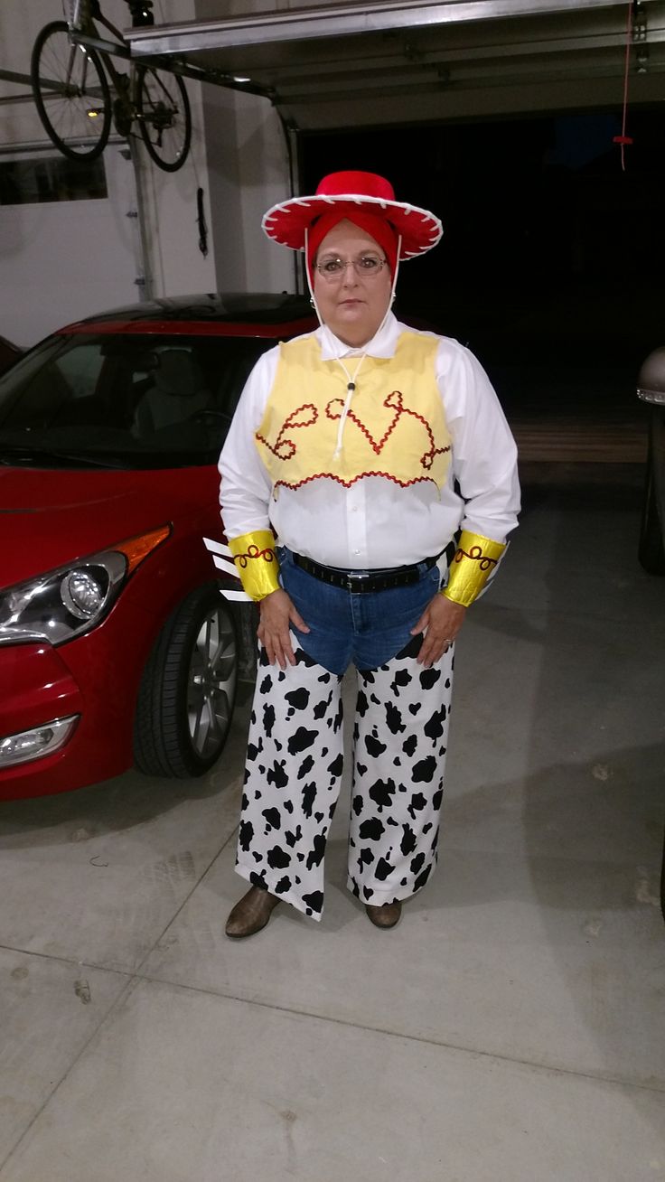 a woman standing in front of a red car wearing cow print pants and a white shirt