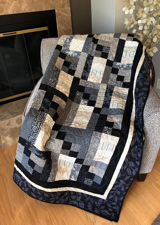 a black and white quilt sitting on top of a chair next to a fire place