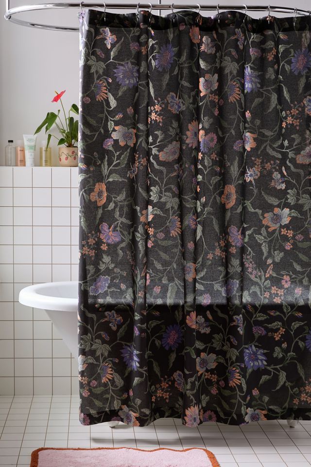 a bathroom with a floral shower curtain and rug