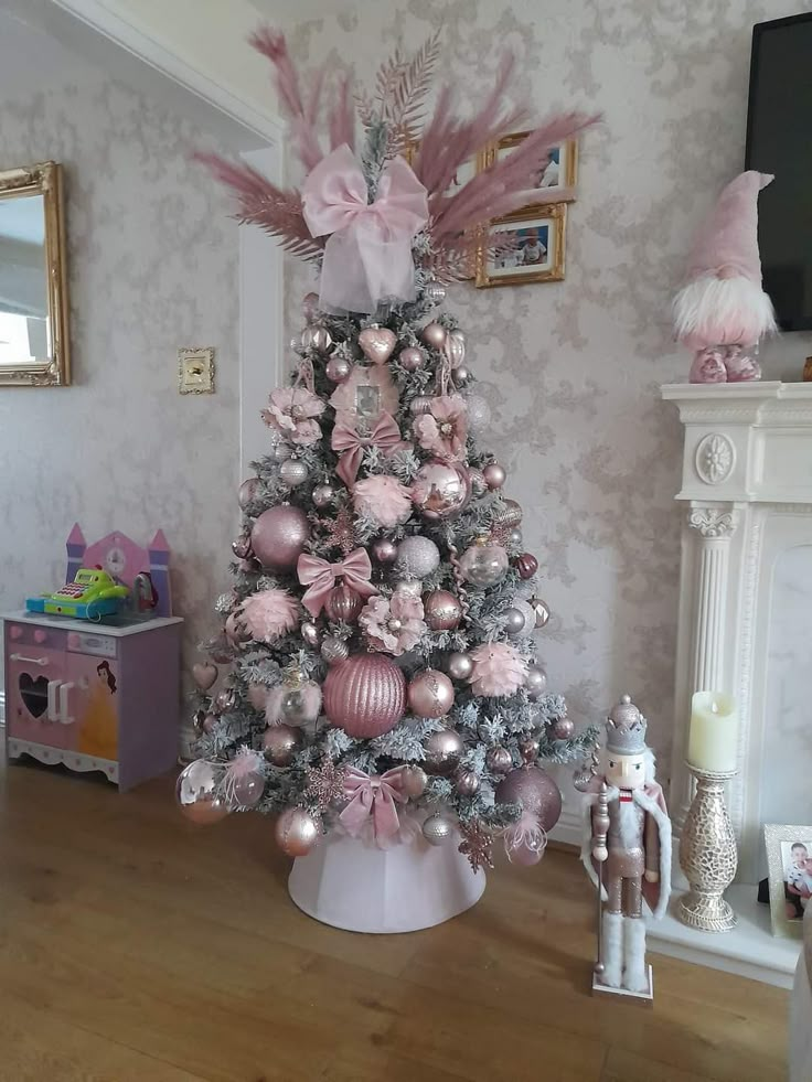 a pink and silver christmas tree in a living room with ornaments on the top,