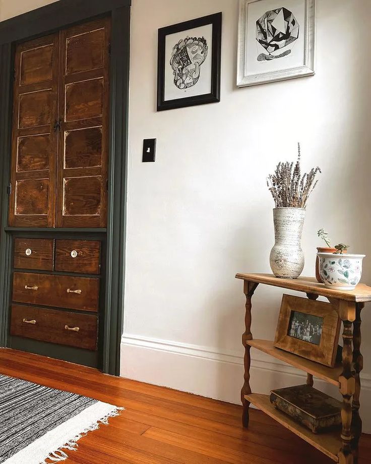 a room with a wooden door and some pictures on the wall next to a rug