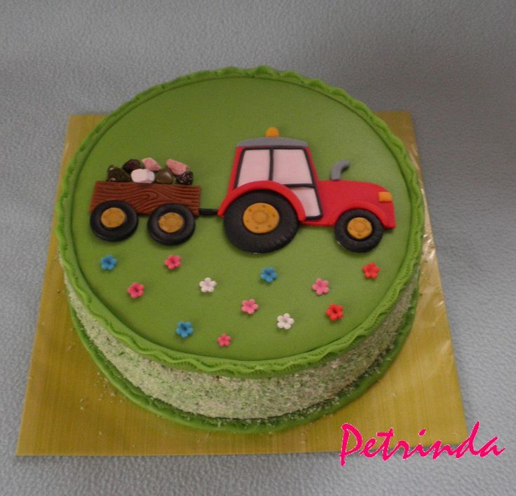 a green cake with a red tractor on it's side and flowers around the edges