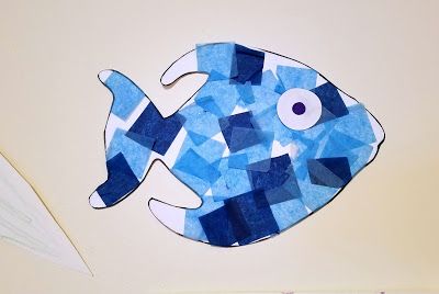 a paper cut out of a blue fish sitting on top of a table