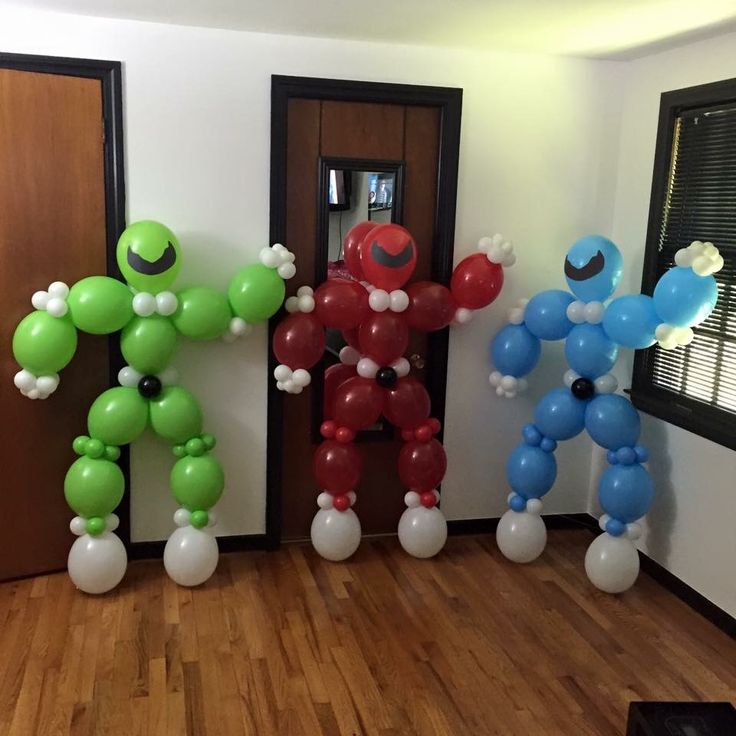 some balloons are in the shape of cartoon characters on a wooden floor and one balloon is shaped like an iron man