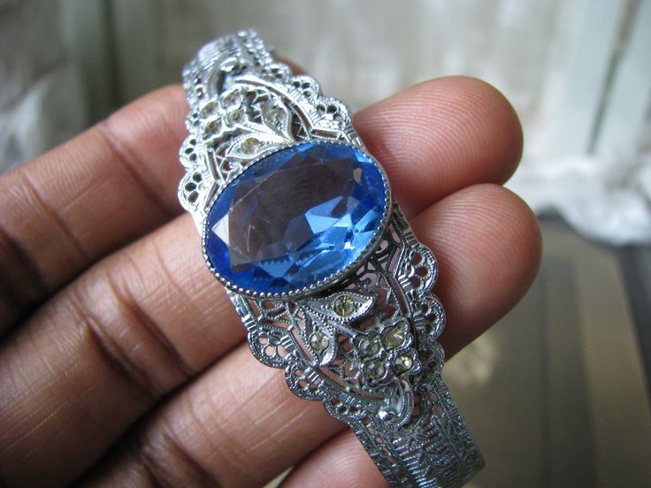 A beautiful Art Deco blue and clear paste floral filigree bangle bracelet. It measures 3/4'' at widest Measures 2 3/8'' x 2'' across the inside, and is 6 3/4'' along the inside. in very good condition with some graying and yellowing to the clear paste stones Filigree Bangle, Art Deco Locket, Nottingham Lace, Bracelet Art, Floral Filigree, Antique Filigree, Round Locket, Art Deco Bracelet, Deco Blue