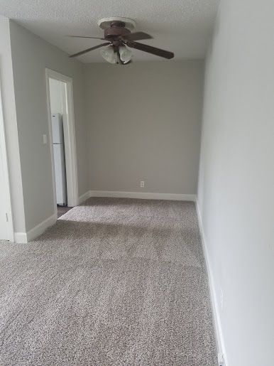 an empty room with carpet and ceiling fan