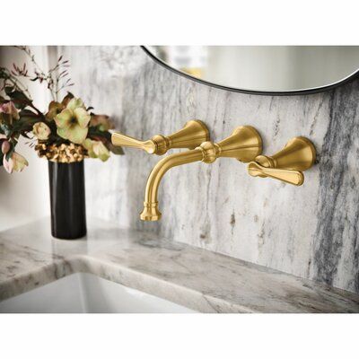 a gold faucet on a marble counter top next to a vase with flowers